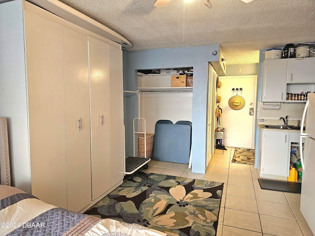 bedroom with light tile patterned floors, a textured ceiling, ceiling fan, and sink