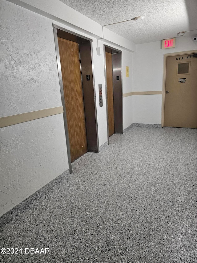 corridor with a textured ceiling and elevator