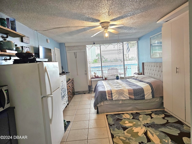 tiled bedroom featuring ceiling fan, white fridge, and a textured ceiling