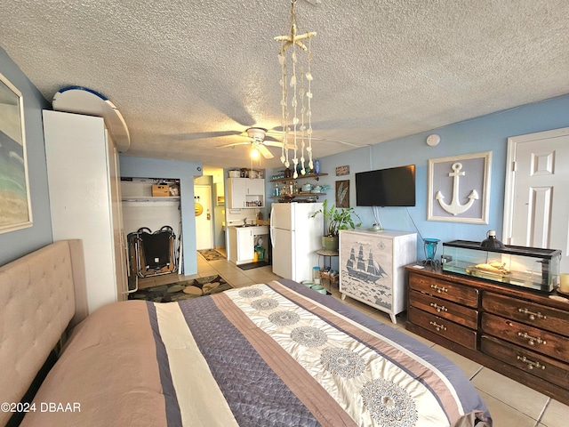 bedroom featuring white fridge, light tile patterned floors, and a textured ceiling