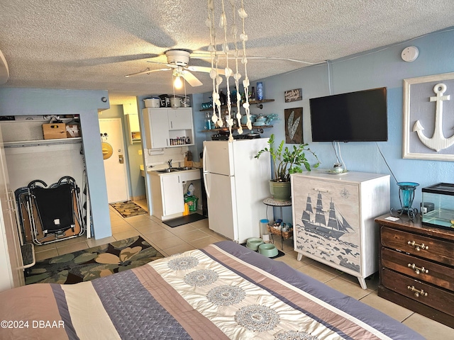 bedroom featuring light tile patterned floors, a textured ceiling, white fridge, and sink