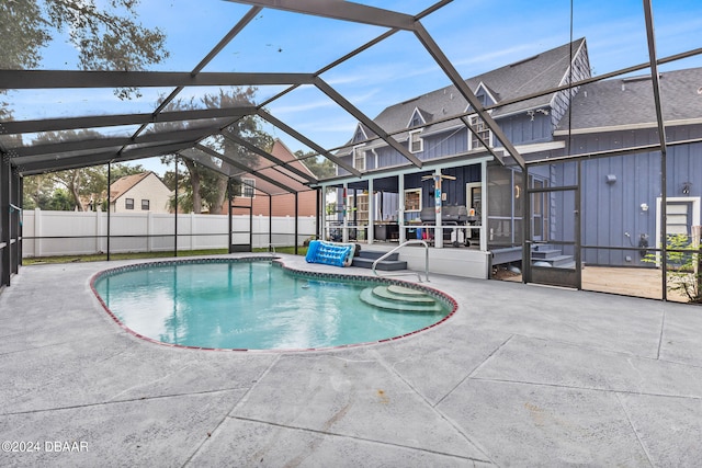 view of swimming pool featuring glass enclosure, ceiling fan, and a patio area