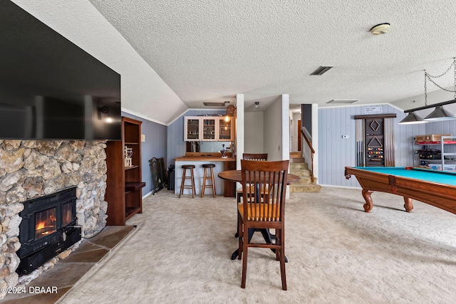 recreation room featuring a fireplace, wooden walls, a textured ceiling, and carpet floors