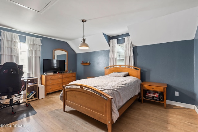 bedroom with hardwood / wood-style floors, multiple windows, and lofted ceiling