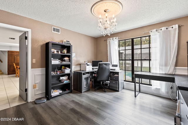 office area with a textured ceiling, hardwood / wood-style flooring, and a chandelier