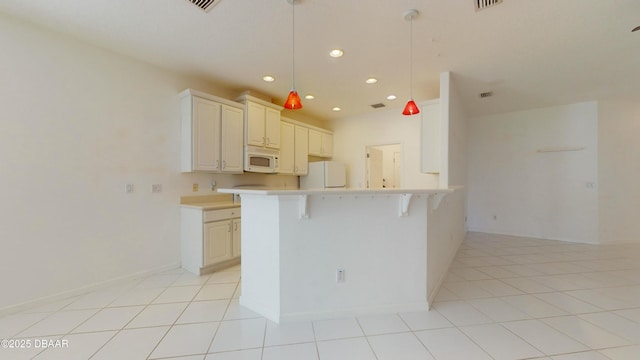 kitchen featuring light tile patterned floors, white appliances, a breakfast bar area, hanging light fixtures, and kitchen peninsula