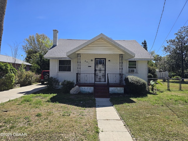 bungalow-style house with brick siding, a chimney, covered porch, a front yard, and fence