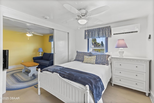 bedroom with ceiling fan, light hardwood / wood-style floors, a closet, and a wall mounted AC