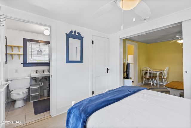 bedroom featuring ceiling fan, ensuite bath, and light tile patterned floors