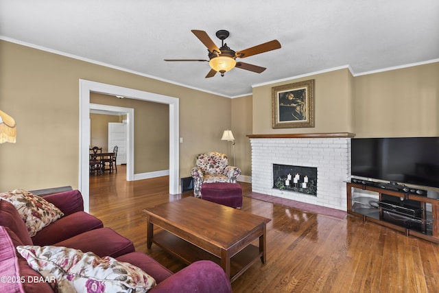 living room with crown molding, ceiling fan, dark hardwood / wood-style floors, and a brick fireplace