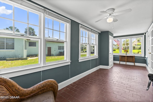 unfurnished sunroom featuring ceiling fan and plenty of natural light