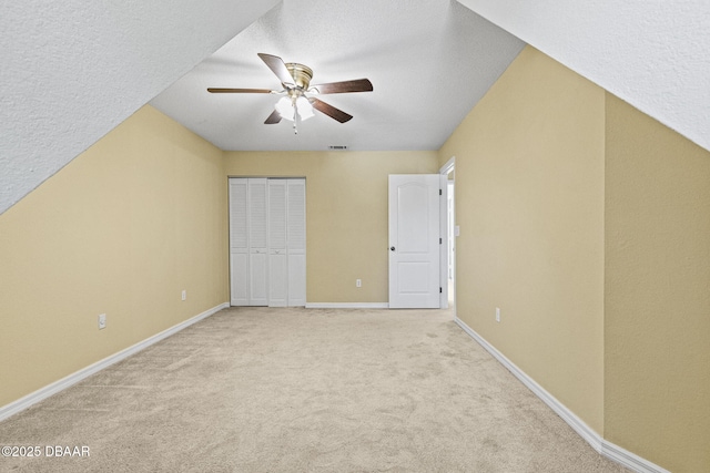 unfurnished bedroom featuring light carpet, a ceiling fan, visible vents, baseboards, and a closet