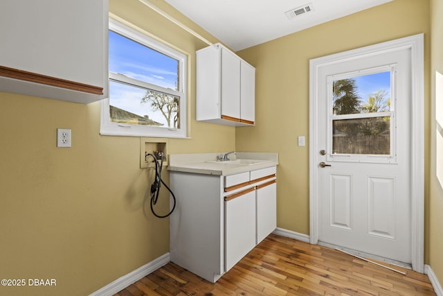 laundry room featuring washer hookup, visible vents, light wood-style flooring, a sink, and baseboards