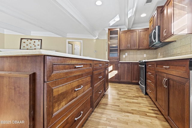 kitchen with light wood-style floors, light countertops, ornamental molding, appliances with stainless steel finishes, and backsplash