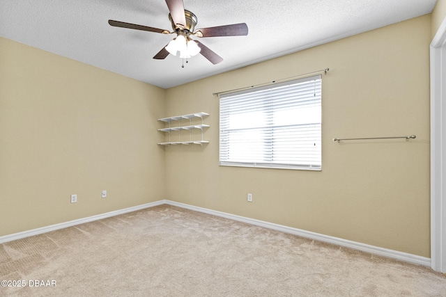 empty room with a ceiling fan, light carpet, a textured ceiling, and baseboards