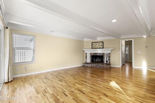 unfurnished living room featuring light wood-style flooring, baseboards, ornamental molding, a brick fireplace, and beamed ceiling