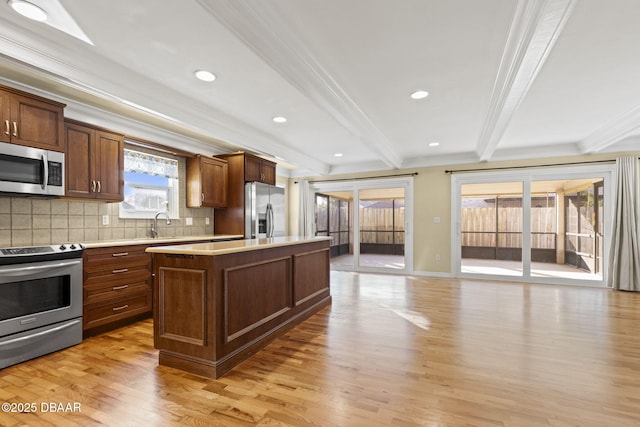 kitchen featuring stainless steel appliances, a kitchen island, light wood-style floors, light countertops, and beamed ceiling