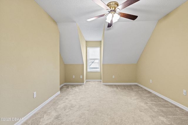 bonus room with ceiling fan, a textured ceiling, light colored carpet, baseboards, and vaulted ceiling