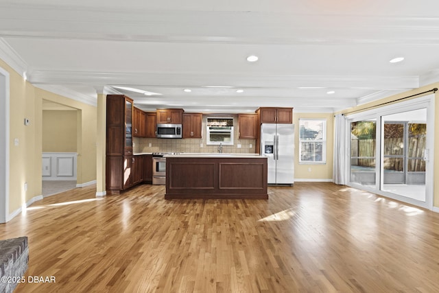 kitchen with tasteful backsplash, glass insert cabinets, stainless steel appliances, light countertops, and light wood-style floors