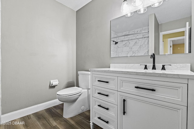 bathroom featuring baseboards, vanity, toilet, and wood finished floors