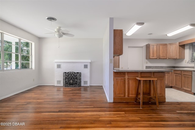 38 Lorillard Pl, Ormond Beach, FL 32174 - kitchen featuring wood finished floors, ceiling fan, a fireplace, a breakfast bar, and dishwashing machine
