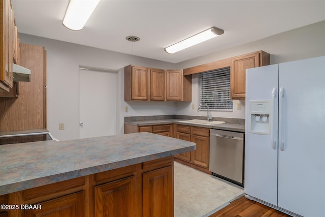 38 Lorillard Pl, Ormond Beach, FL 32174 - kitchen featuring white fridge with ice dispenser, stainless steel dishwasher, a peninsula, brown cabinetry, and under cabinet range hood