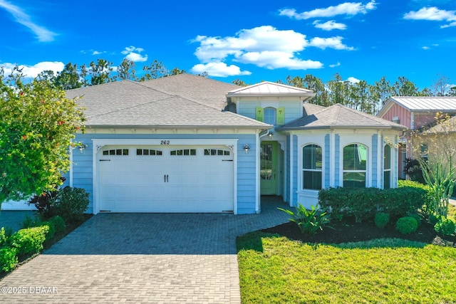 view of front of home with decorative driveway, a garage, and roof with shingles