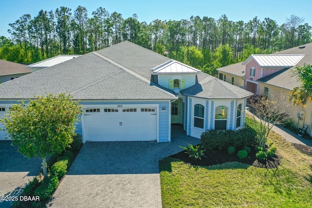 view of front of house featuring decorative driveway, a garage, and a shingled roof