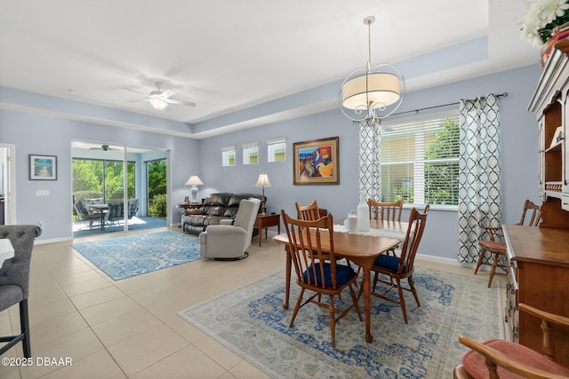 tiled dining area with baseboards, a raised ceiling, and a ceiling fan