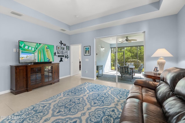 tiled living area featuring a tray ceiling, baseboards, visible vents, and ceiling fan