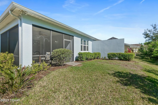 exterior space featuring stucco siding, a lawn, and a sunroom