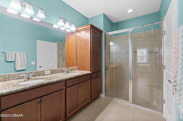 bathroom featuring tile patterned flooring, a shower stall, double vanity, and a sink