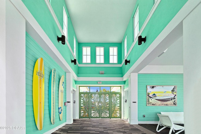 entryway with wooden walls, a high ceiling, and baseboards