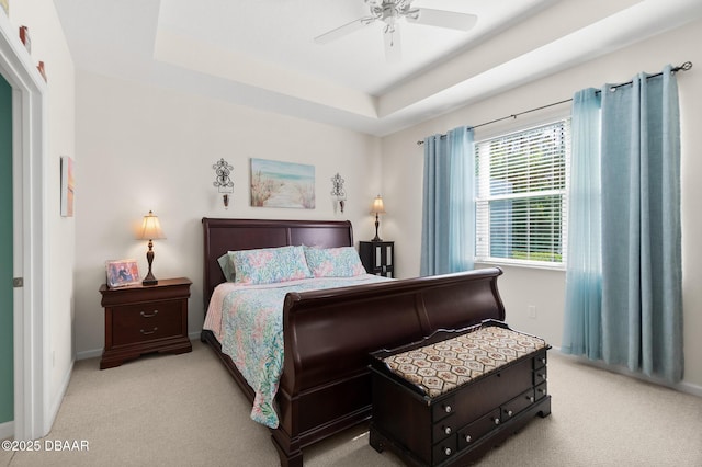 carpeted bedroom with a tray ceiling and ceiling fan