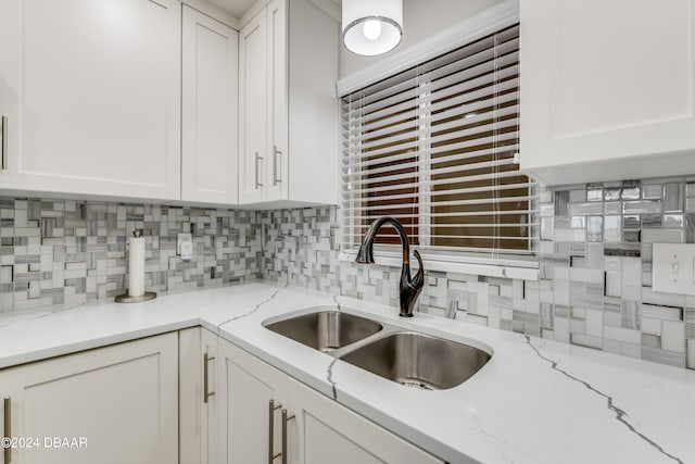 kitchen featuring decorative backsplash, sink, light stone counters, and white cabinets