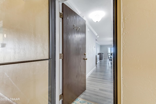 hallway with hardwood / wood-style floors and ornamental molding