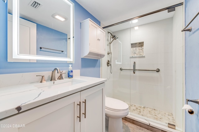 bathroom with hardwood / wood-style floors, vanity, toilet, and a shower with shower door