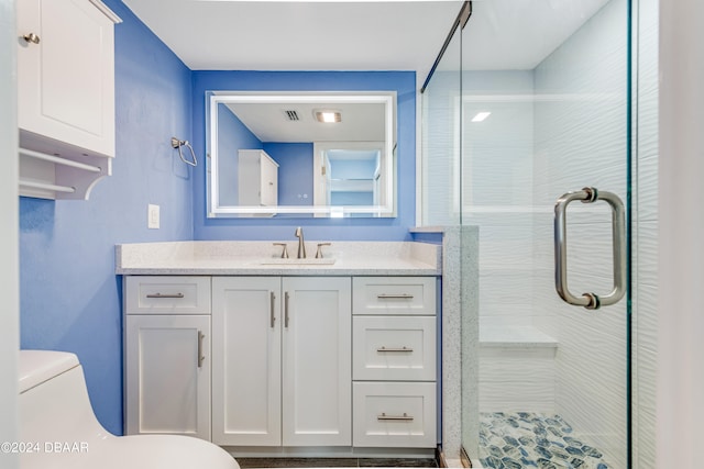 bathroom with vanity, toilet, and a shower with door