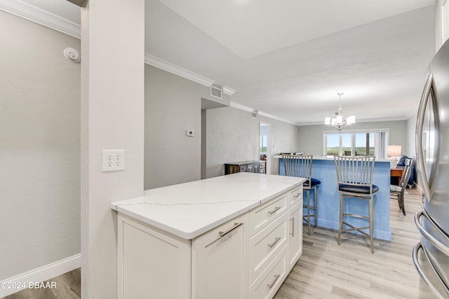 kitchen with light stone countertops, stainless steel fridge, white cabinetry, and light hardwood / wood-style floors