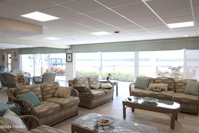 tiled living room with a paneled ceiling and a water view