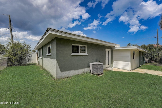 rear view of house featuring a lawn and central AC unit