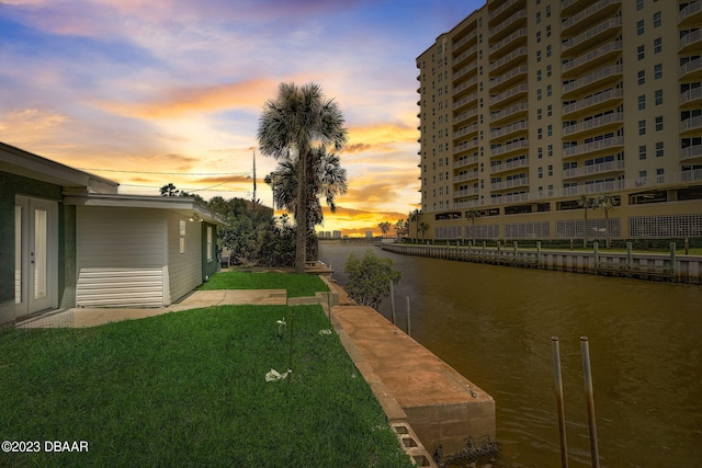 yard at dusk featuring a water view