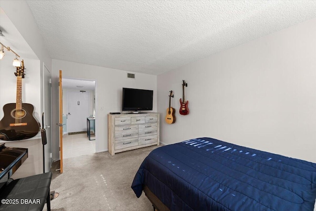 bedroom with light colored carpet and a textured ceiling