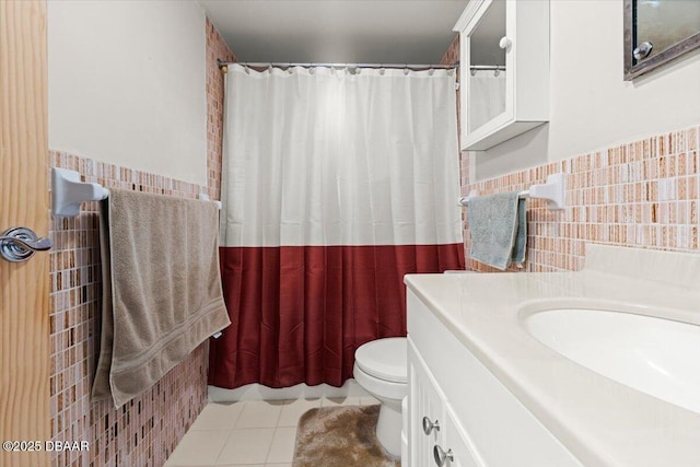 bathroom with tile patterned flooring, vanity, toilet, and tile walls