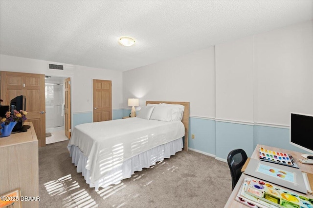 bedroom featuring carpet flooring, ensuite bathroom, and a textured ceiling