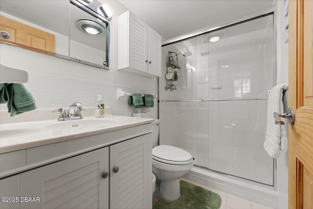 bathroom with vanity, a shower with door, tile patterned floors, toilet, and tile walls