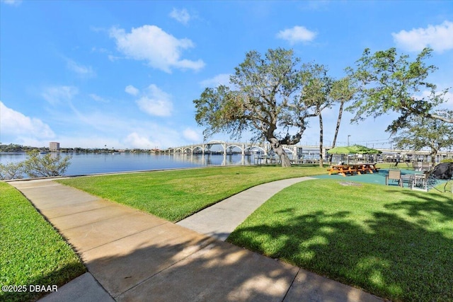 view of property's community with a lawn and a water view