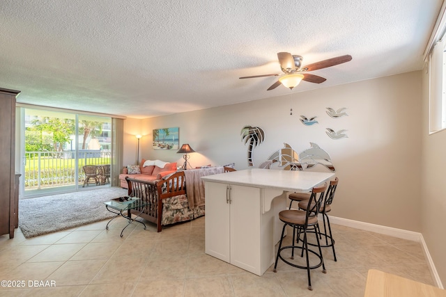 2727 N Atlantic Ave Unit 107, Daytona Beach, FL 32118 - kitchen featuring a kitchen breakfast bar, a textured ceiling, light countertops, a ceiling fan, and light tile patterned flooring