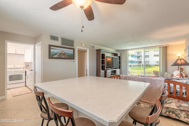 2727 N Atlantic Ave Unit 107, Daytona Beach, FL 32118 - kitchen featuring electric stove, a textured ceiling, a breakfast bar area, ceiling fan, and a kitchen island