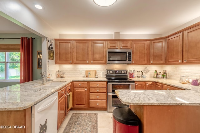 kitchen with light stone countertops, sink, kitchen peninsula, and stainless steel appliances